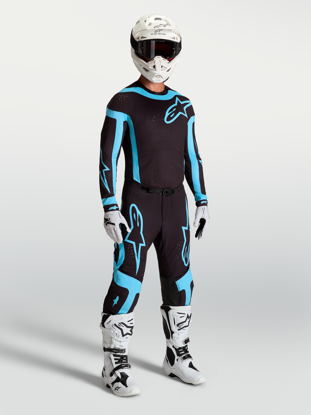 Alpinestars Supertech Vesta Hose, Motocross-Rennbekleidung für Herren in Schwarz und Türkis mit weißen Stiefeln und Helm.