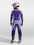 Alpinestars Supertech Vesta Trikot und Hose, Motocross-Rennausrüstung in Blau und Weiß, Rückansicht am Model mit Helm und Stiefeln.