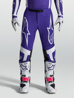 Alpinestars Supertech Vesta Hose, Motocross-Hose in Blau und Weiß, athletische Passform mit robuster Ripstop-Konstruktion, getragen mit Offroad-Stiefeln.