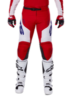 Alpinestars 2025 Racer Veil Hose, Motocross-Hose, Leuchtendes Rot und Weiß, getragen mit passenden roten Handschuhen und weißen Stiefeln, mit blauem Branding an den Oberschenkeln und einem schwarzen Taillengürtel, ergonomischer Sport-Schnitt für Performance-Fahren