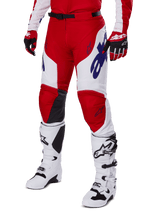 Alpinestars 2025 Racer Veil Pants, Motocross Pants, Bright Red and White, featuring blue Alpinestars logos and black leather inner knee panels, worn with matching red gloves and white motocross boots, coordinated gear set for off-road racing