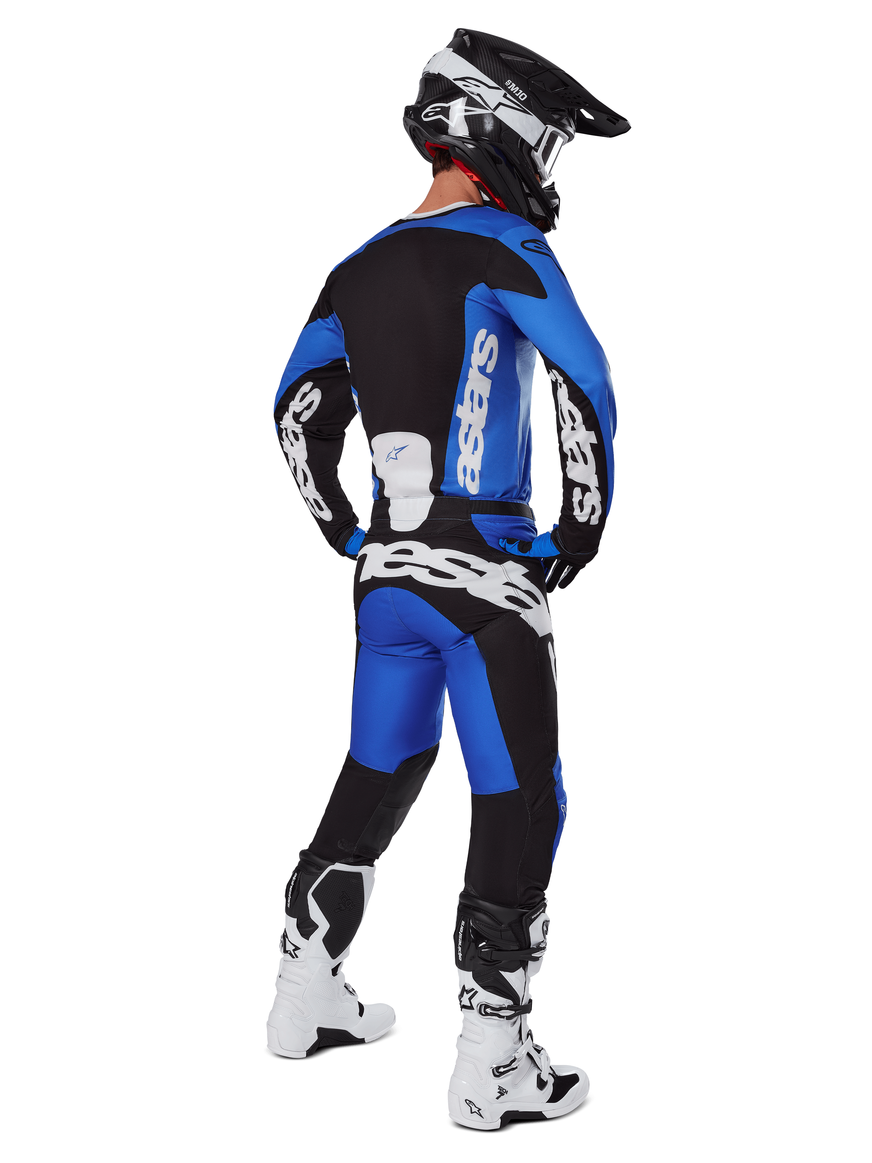 Motocross-Fahrer in der Rückansicht, trägt Alpinestars 2025 Racer Veil Hose in Blau und Schwarz, passendes Langarm-Trikot mit weißem Branding, weiß-schwarze Tech 7 Stiefel und einen schwarzen SM10 Helm, komplettes Offroad-Racing-Gear-Set