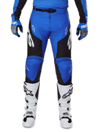 Alpinestars 2025 Racer Veil Hose, Motocross-Hose, Blau und Schwarz, mit weißen Alpinestars-Logos an den Beinen, schwarzen Seiteneinsätzen, getragen mit weißen Motocross-Stiefeln und blau-grauen Handschuhen, Hochleistungs-Offroad-Ausrüstung