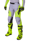 Alpinestars 2025 Racer Veil Hose, Motocross-Hose, Grau und Neongelb Fluo, mit schwarzen Stern-Logos und verstellbarem Hüftgurt, abgebildet mit passenden Motocross-Stiefeln und Handschuhen, ergonomisches Design für den Offroad-Einsatz