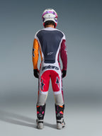 Motocross rider viewed from behind wearing the 2026 Racer Portl Pants in Red, Light Gray, and Dark Gray, featuring "astars" branding across the seat, coordinated with a multi-colored jersey, white helmet, and technical racing boots.