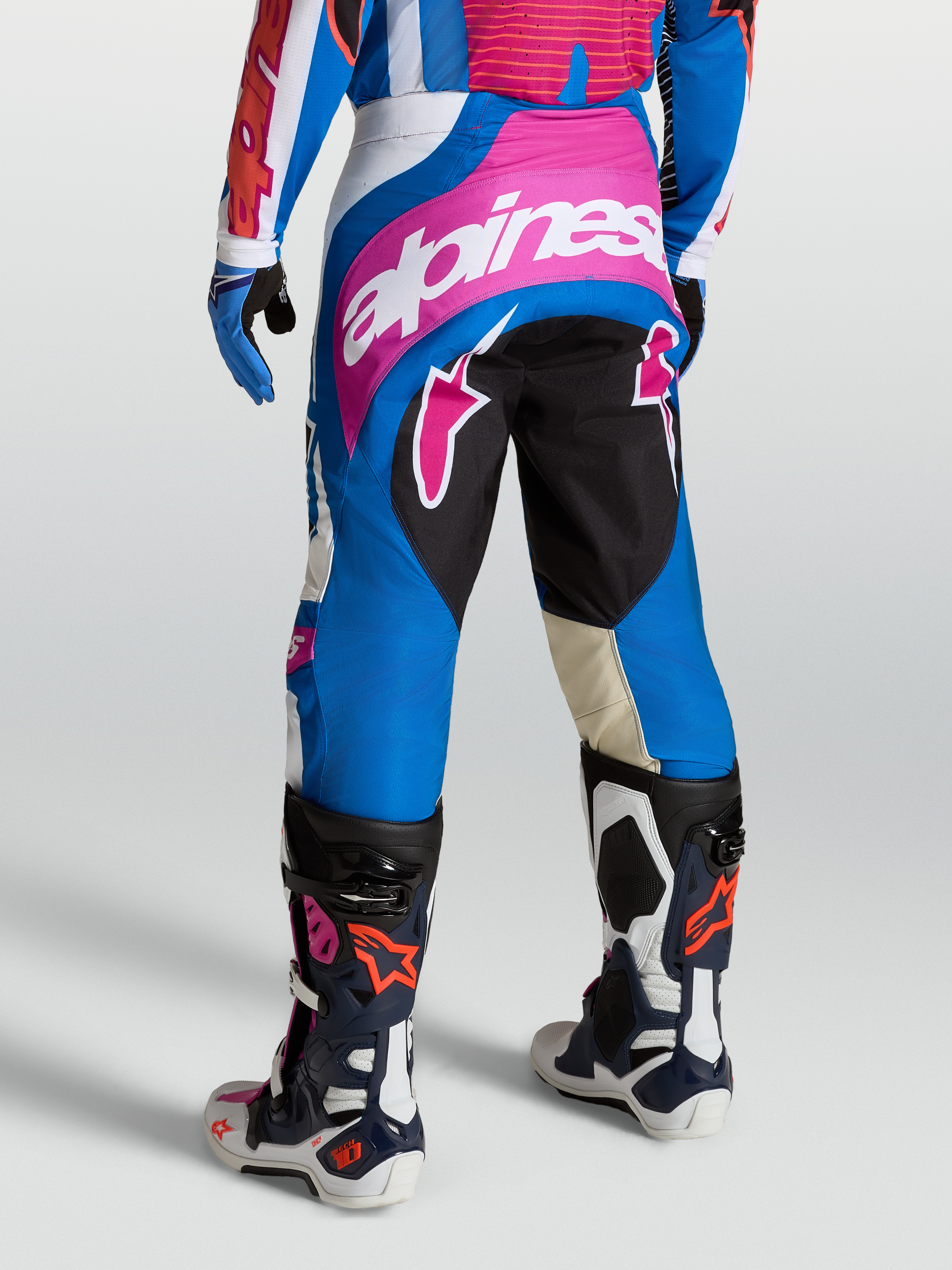 Alpinestars Techstar Maven Hose, Motocross-Hosen für Herren, Blau und Pink, athletische Rennpassform mit verstärktem Sitzbereich, getragen mit Tech-Air kompatibler Racing-Ausrüstung und Stiefeln.