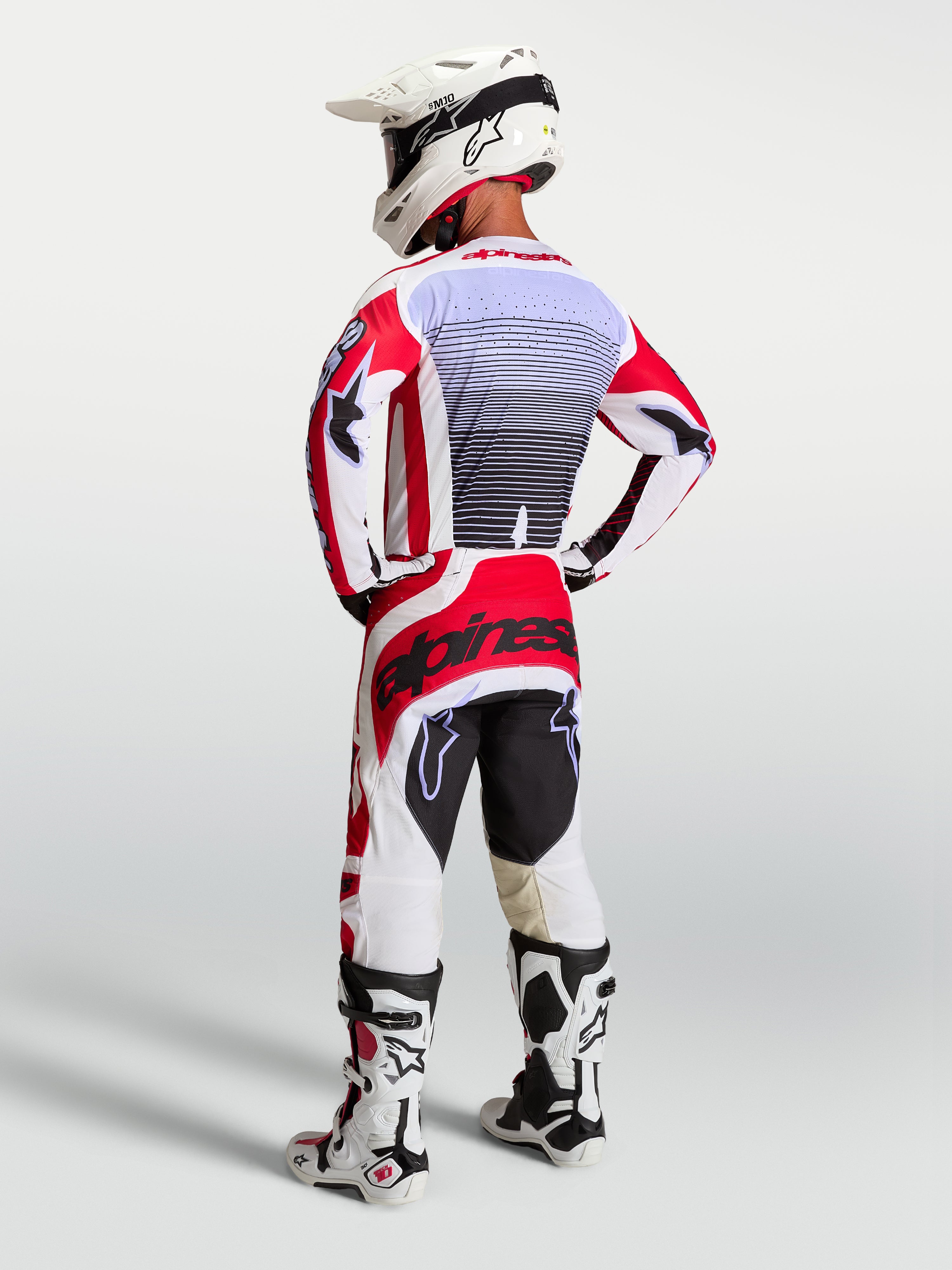 Alpinestars Techstar Maven Hose, Herren-Motocross-Rennhose in Rot und Weiß, Rückansicht am Fahrer mit passendem Trikot.