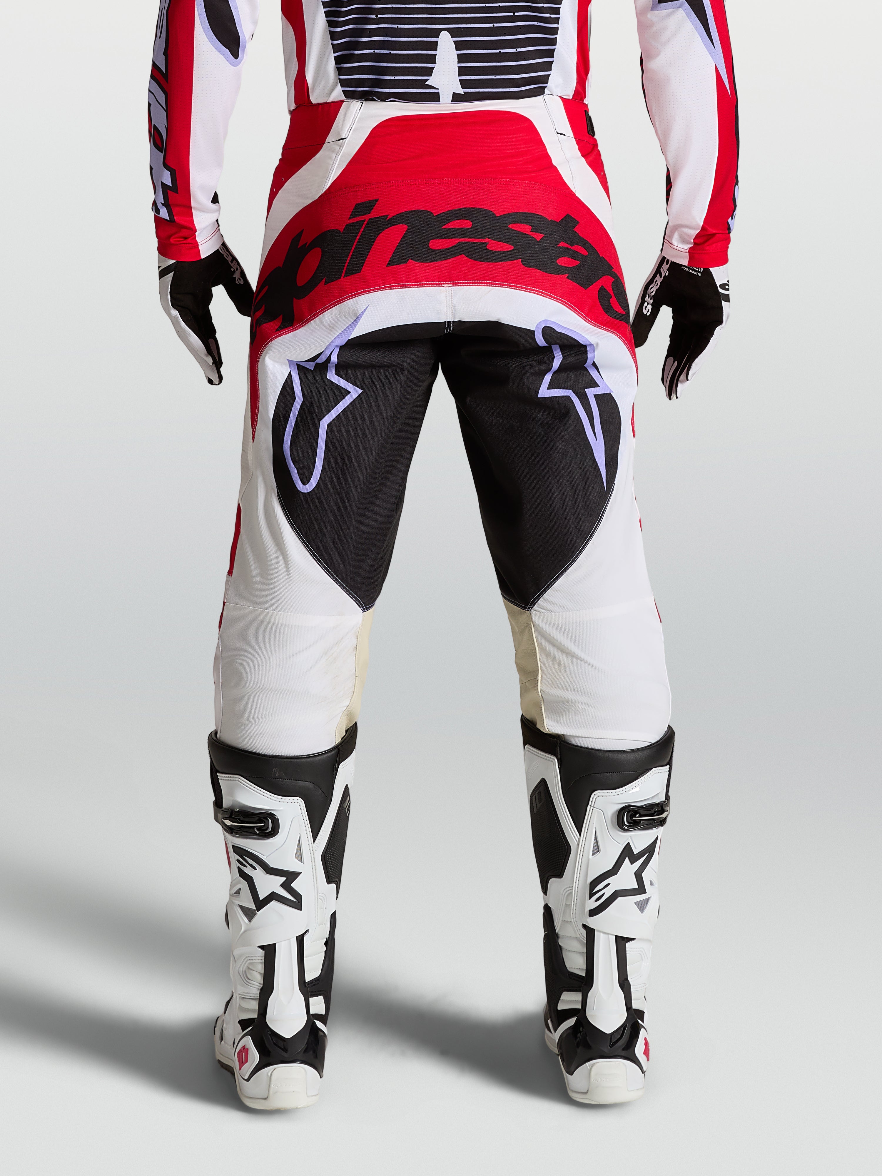 Alpinestars Techstar Maven Hose, Motocrosshose für den Rennsport, Rückansicht am Model, Rot, Weiß und Schwarz, verstärktes Gesäßpanel und athletische Rennpassform.