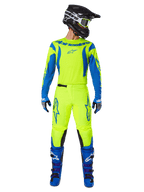Alpinestars 2025 Fluid Haul Hose, Motocross-Hose, Neongelb und Blau, getragen als komplettes Racing-Kit mit passendem Trikot, blauen Stiefeln und schwarzem Helm, mit markantem blauen Branding an den Oberschenkeln und schwarzen Knieeinsätzen