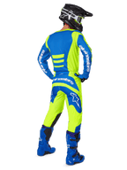 Motocross-Fahrer von hinten in Alpinestars 2025 Fluid Haul Hose und passendem Trikot in Gelb Fluo und Blau, kombiniert mit blauen Stiefeln und einem schwarzen Alpinestars-Helm, professionelle Offroad-Rennausrüstung