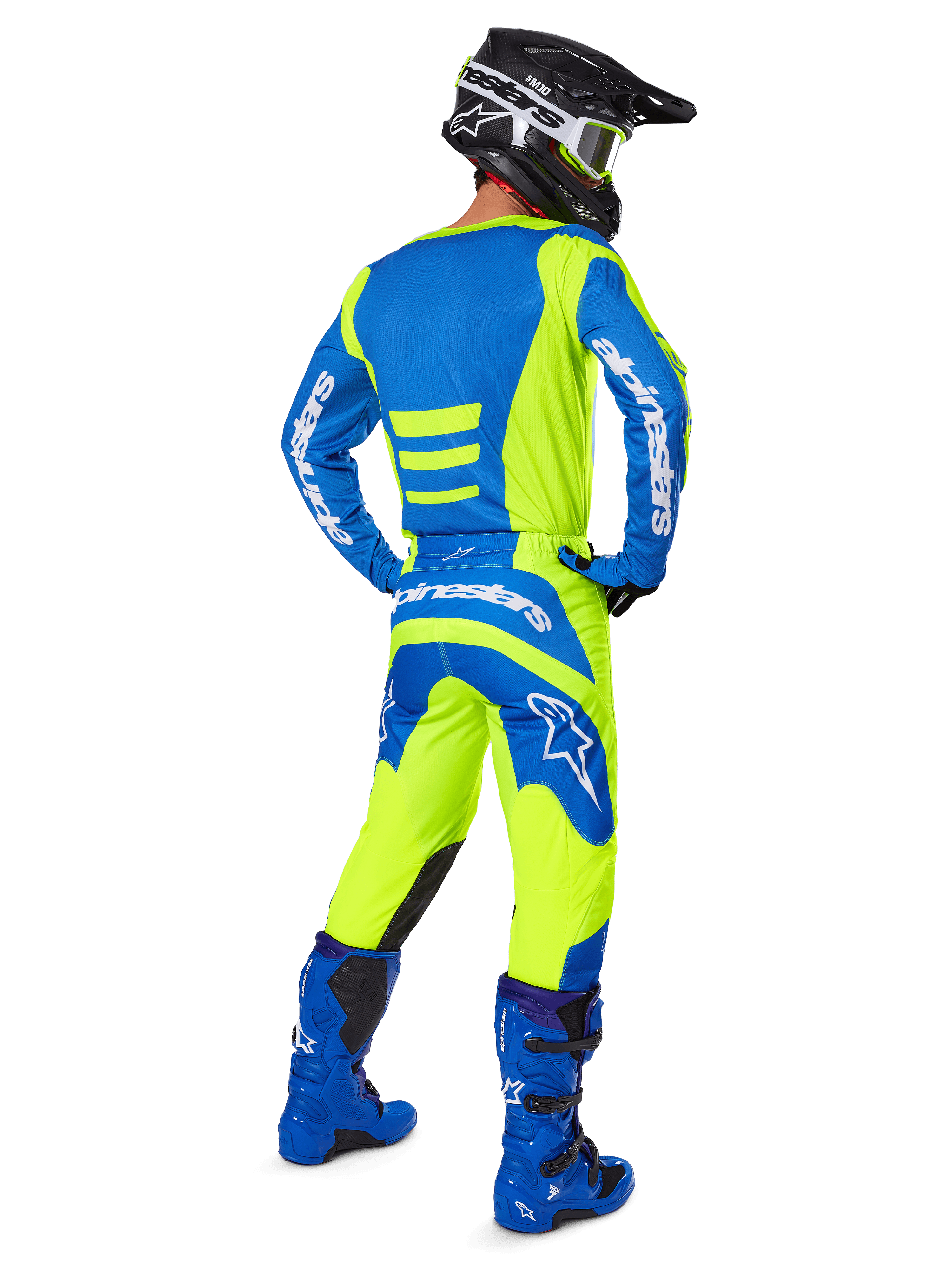 Motocross-Fahrer von hinten in Alpinestars 2025 Fluid Haul Hose und passendem Trikot in Gelb Fluo und Blau, kombiniert mit blauen Stiefeln und einem schwarzen Alpinestars-Helm, professionelle Offroad-Rennausrüstung