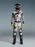 Motocross-Fahrer im Alpinestars 2026 Racer Lahnd Gear Set, Anzug mit Sand-Camo-Muster in Weiß, Grau und Schwarz, schwarzer Helm mit neongrüner Brille, leuchtend neongrüne Handschuhe und schwarze Stiefel mit weißen Logos, komplettes koordiniertes Outfit für den Offroad-Rennsport