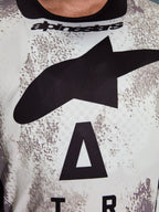 Alpinestars 2026 Racer Lahnd Jersey, Motocross-Jersey, weiß-grau gesprenkeltes Muster, Nahaufnahme der Brust mit großem schwarzem Astars-Logo und Alpinestars-Branding am Halsausschnitt, performance-orientiertes Design für den Offroad-Einsatz