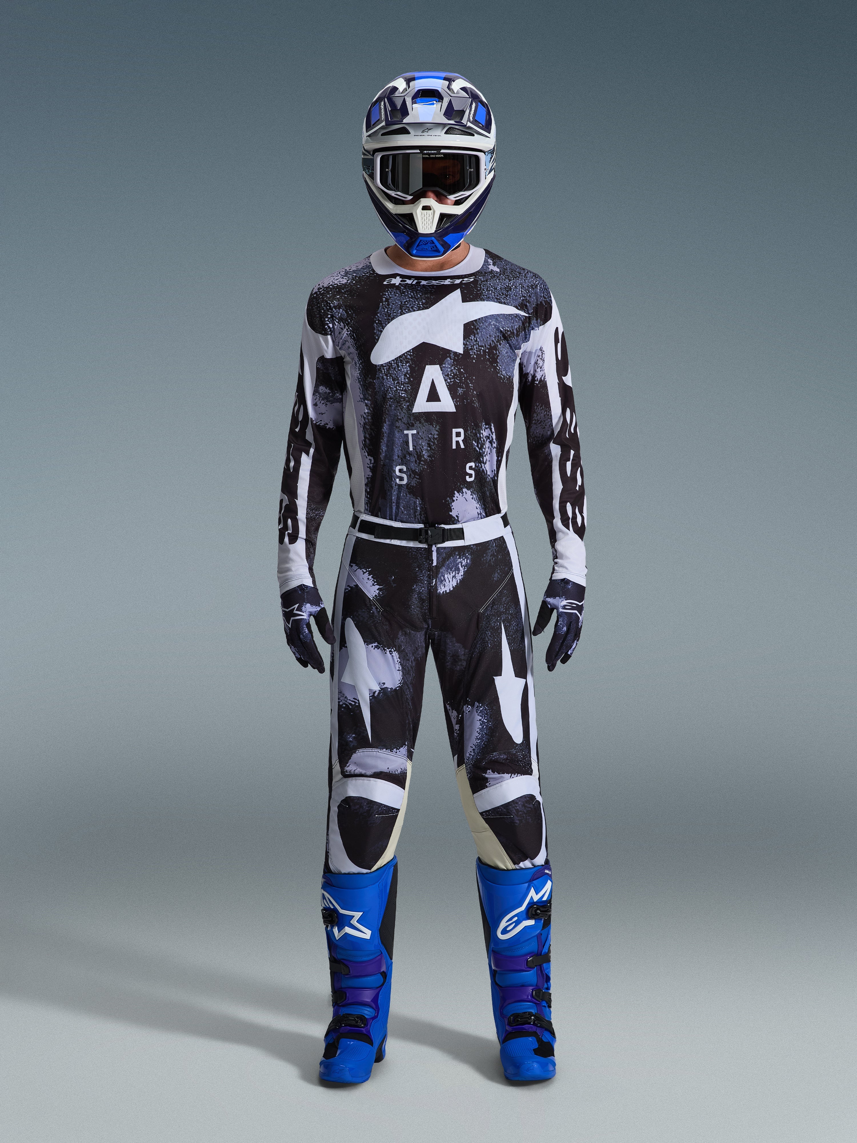 Alpinestars 2026 Racer Lahnd Gear Set, Motocross Outfit, Black and White with Iron Camo abstract pattern, paired with blue and white helmet and bright blue boots, complete racing kit for off-road performance
