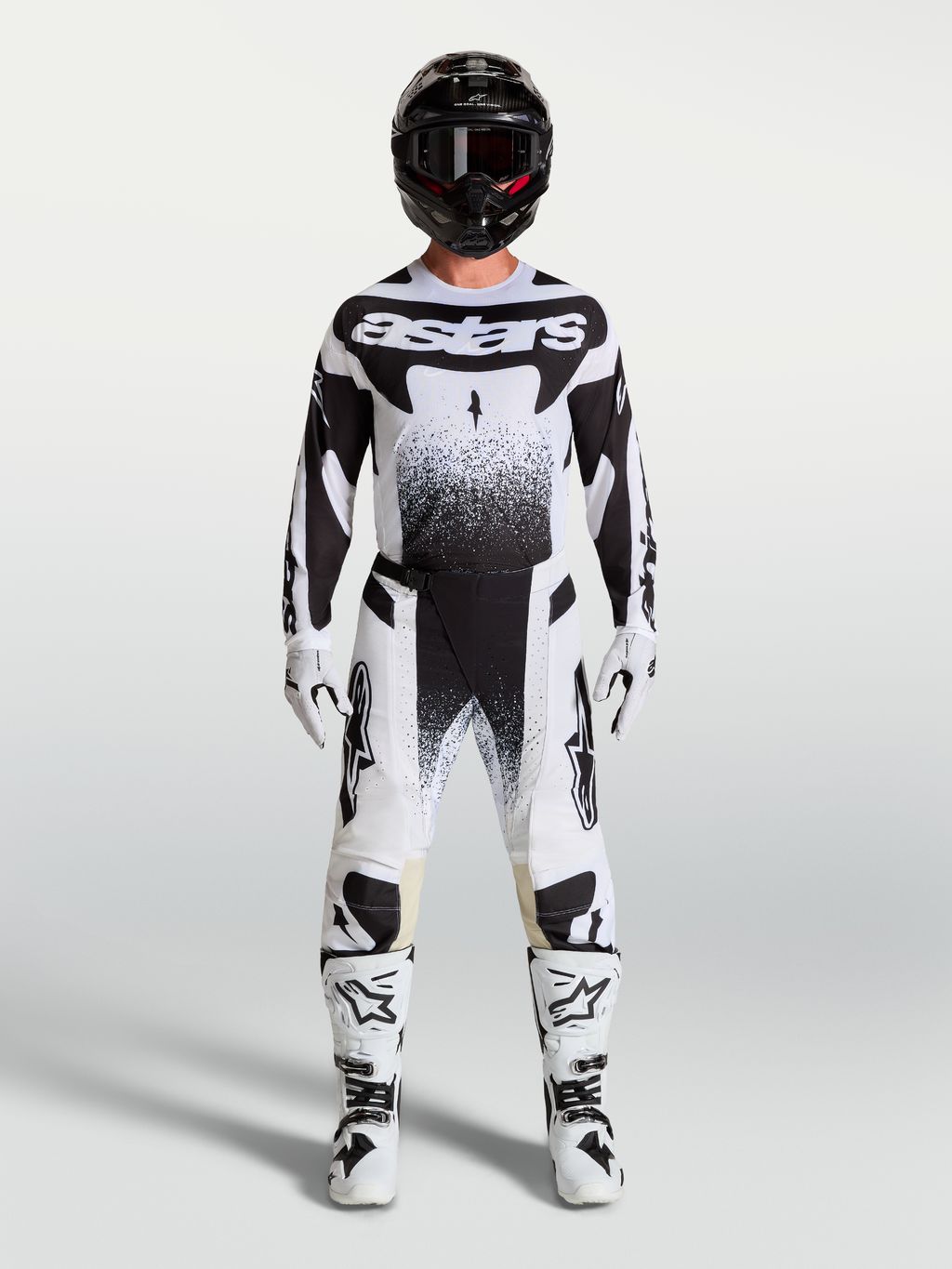 Alpinestars Techstar Swan Hose und Trikot, Motocross-Rennausrüstung für Herren, Weiß und Schwarz, getragen von einem Model mit passenden MX-Stiefeln und Helm