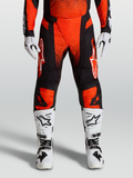 Alpinestars Techstar Swan Hose 2027, Motocrosshose in Kardinalrot und Schwarz, mit weißen Stiefeln und Handschuhen.