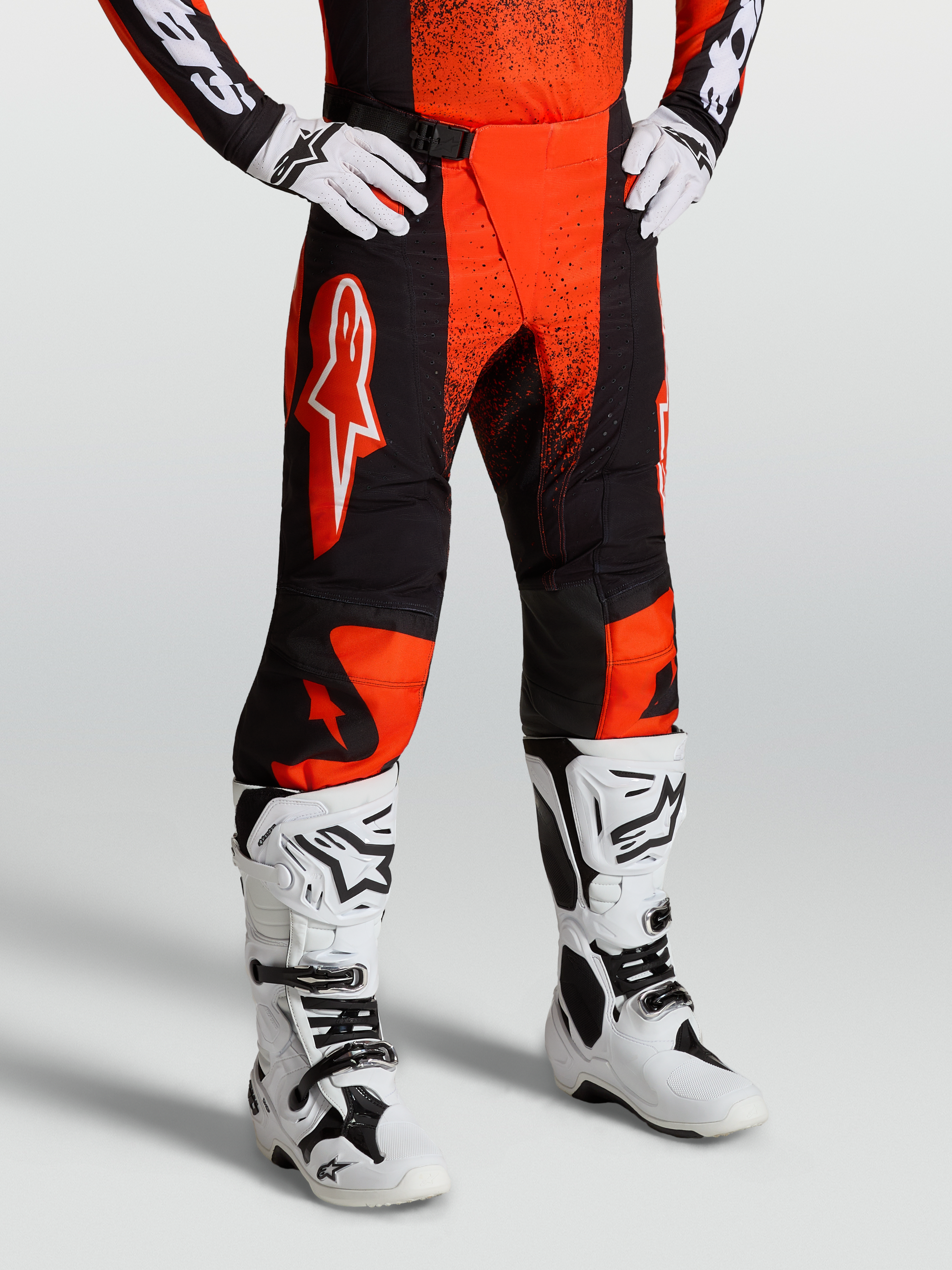 Alpinestars Techstar Swan Hose, Motocross-Hose für Herren, Cardinal Rot und Schwarz, robustes Ripstop-Gewebe mit 4-Wege-Stretch-Einsätzen, getragen mit weißen Offroad-Stiefeln.