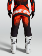 Alpinestars Techstar Swan Hose, MX-Hose in Rot und Schwarz, Rückansicht am Model mit weißem Astars-Logo und weißen Rennstiefeln, Offroad-Motocross-Ausrüstung