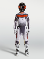 Alpinestars Techstar Swan Hose, Herren-Motocross-Set in Helllila, Dunkelgrau und Leuchtrot mit weißen Motorradstiefeln.