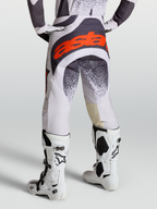 Alpinestars Techstar Swan Hose, Motocross-Hose für Herren, Helllila und Dunkelgrau mit roten Akzenten, kombiniert mit weißen Tech 10 Stiefeln, Rückansicht.