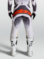 Alpinestars Techstar Swan Hose, Motocross-Hose f$r Herren, Helllila und Dunkelgrau, mit rotem Astars-Logo auf dem Ges$$bereich, kombiniert mit wei$en Motocross-Stiefeln.
