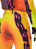Alpinestars 2025 Supertech Lipan Hose, Nahaufnahme der Rück- und Seitenansicht, gelber und oranger Farbverlauf mit markantem Alpinestars-Branding in Pink und Schwarz, professionelle Motocross-Ausrüstung