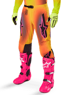 Alpinestars 2025 Supertech Lipan Ausrüstungsset, Motocross-Hose, gelb-oranger Farbverlauf mit Akzenten in Pink und Lila, markante schwarze Alpinestars-Logos auf den Oberschenkeln, gelbe Handschuhe und leuchtend pinke Motocross-Stiefel.