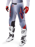 Alpinestars 2025 Supertech Lipan Pants, Motocross Pants, Gray and Orange Fluo, featuring navy star designs and black inner knee panels, worn with red-orange gloves and white boots, professional off-road racing gear