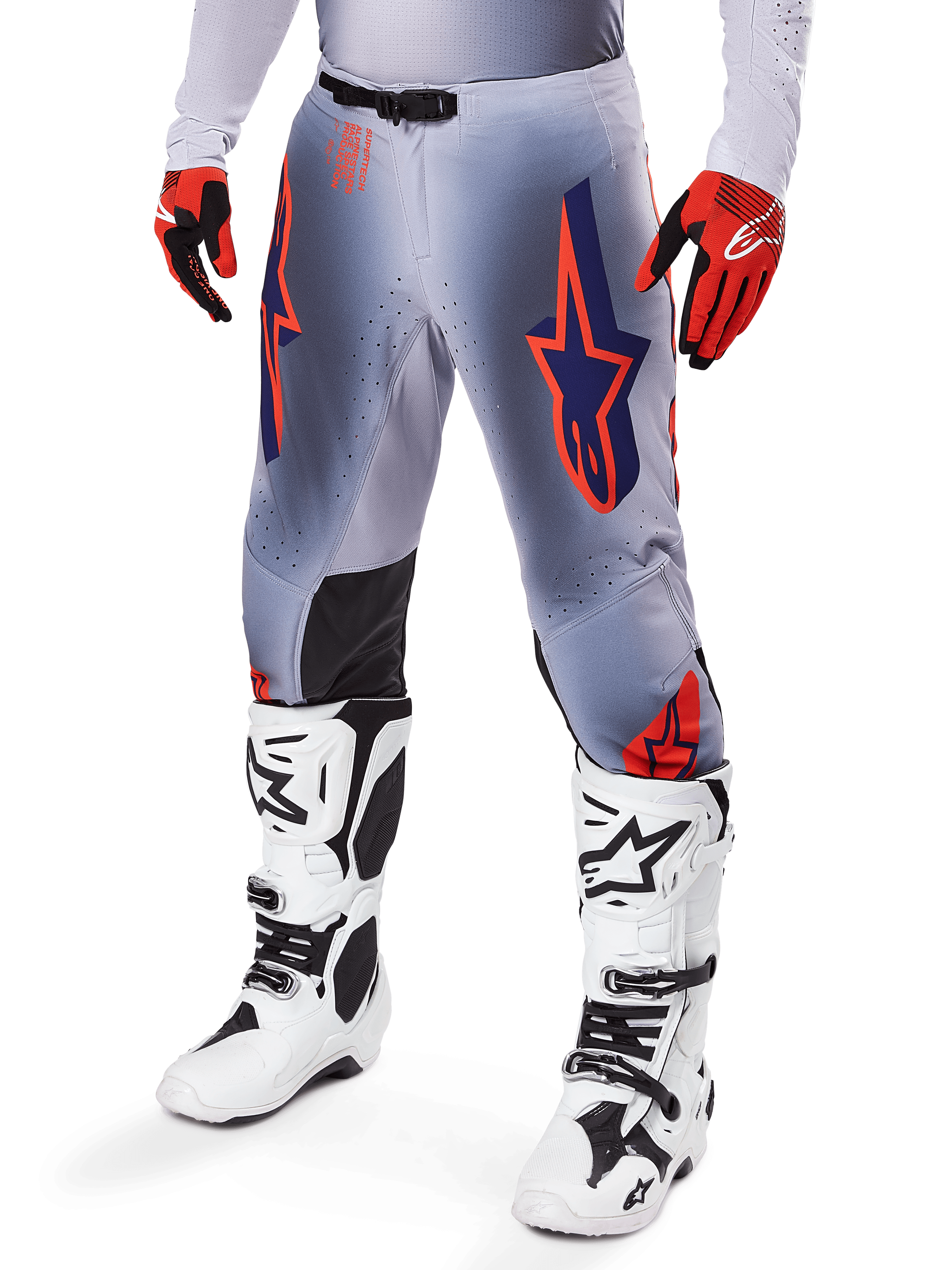 Alpinestars 2025 Supertech Lipan Hose, Motocross-Hose, Grau und Orange Fluo, mit dunkelblauen Sternendesigns und schwarzen Knieinneneinsätzen, getragen mit rot-orangen Handschuhen und weißen Stiefeln, professionelle Offroad-Rennausrüstung