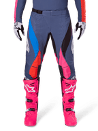 Alpinestars 2025 Techstar Dreem Hose, Motocross-Hose, Grau Mehrfarbig mit pinken, blauen und orangefarbenen Akzenten, getragen mit leuchtend pinken Motocross-Stiefeln und passendem Trikot, athletische Race-Passform mit lasergeschnittenen Belüftungslöchern