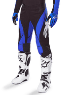 Alpinestars 2025 Techstar Dreem Pants, Motocross Pants, Black and Blue, worn with white motocross boots and blue gloves, featuring white Alpinestars logo on the leg, durable construction for off-road racing