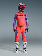 Alpinestars 2026 Supertech Scenz Hose, Motocross-Hose, Hot Coral und Lila, getragen als komplettes Gear-Set mit passendem Trikot und Helm, weiße und schwarze Stiefel, mit lila Logos und athletischer Race-Passform.
