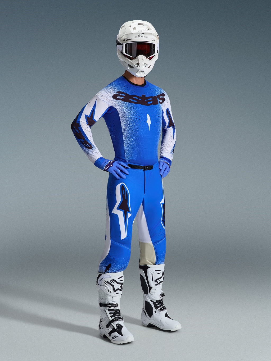 Motocross rider wearing complete racing gear, featuring the 2026 Supertech Scenz Pants in Ucla Blue and White, matching blue and white jersey with Astars logo, white helmet with red goggles, and white and black boots, coordinated outfit for professional off-road racing.