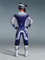 Alpinestars 2026 Supertech Scenz Pants, Motocross Pants, Light Gray and Dark Blue, rear view of a rider wearing a matching gear set with speckled gradient graphics, white boots and black helmet, professional athletic fit for off-road racing