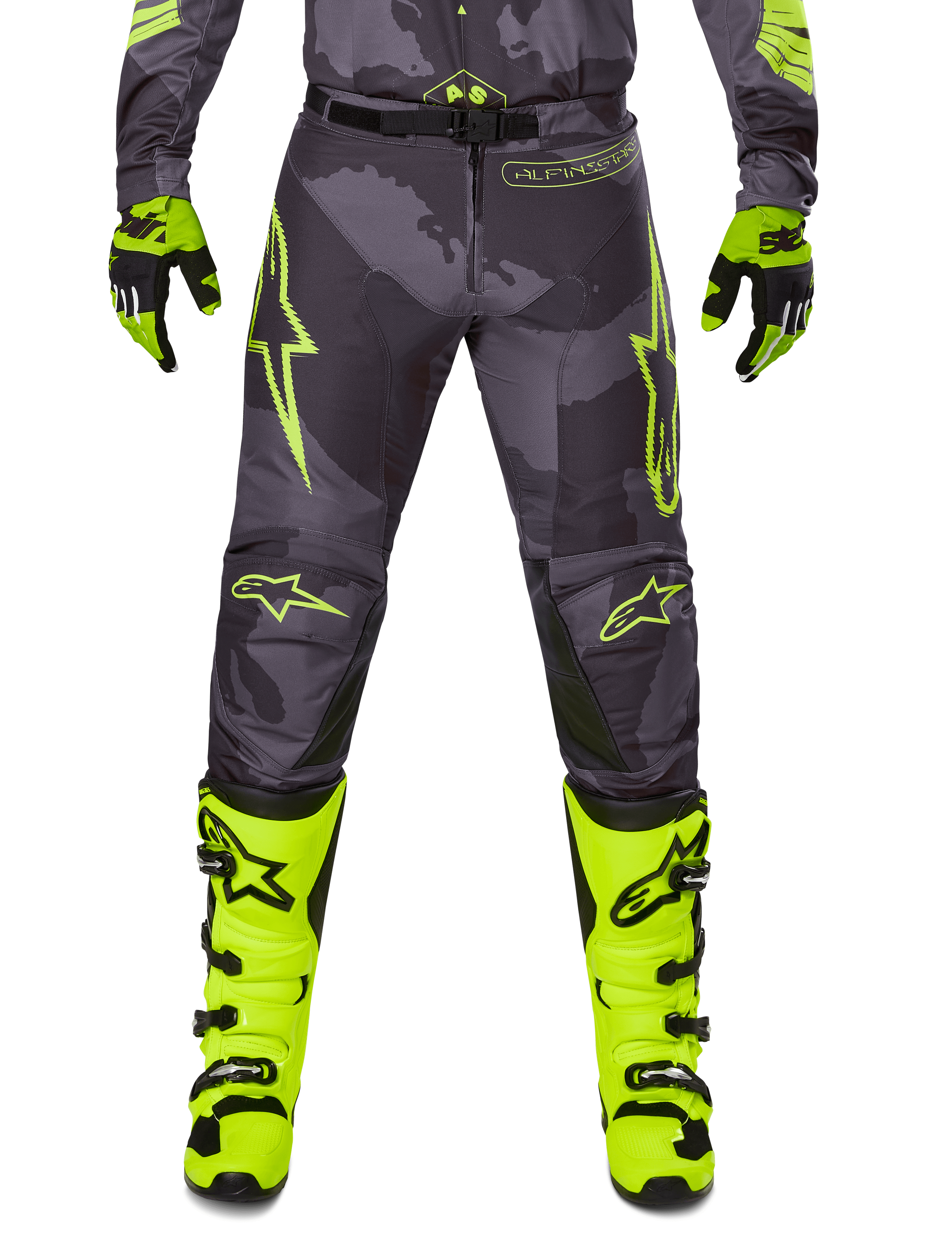 Alpinestars 2025 Racer Hollow Hose, Motocross-Hose, Dunkelgrau mit Neongelb, Sterndesigns und Logo, Person trägt komplette Offroad-Schutzausrüstung mit schwarzen und neongelben Handschuhen und neongelben Stiefeln