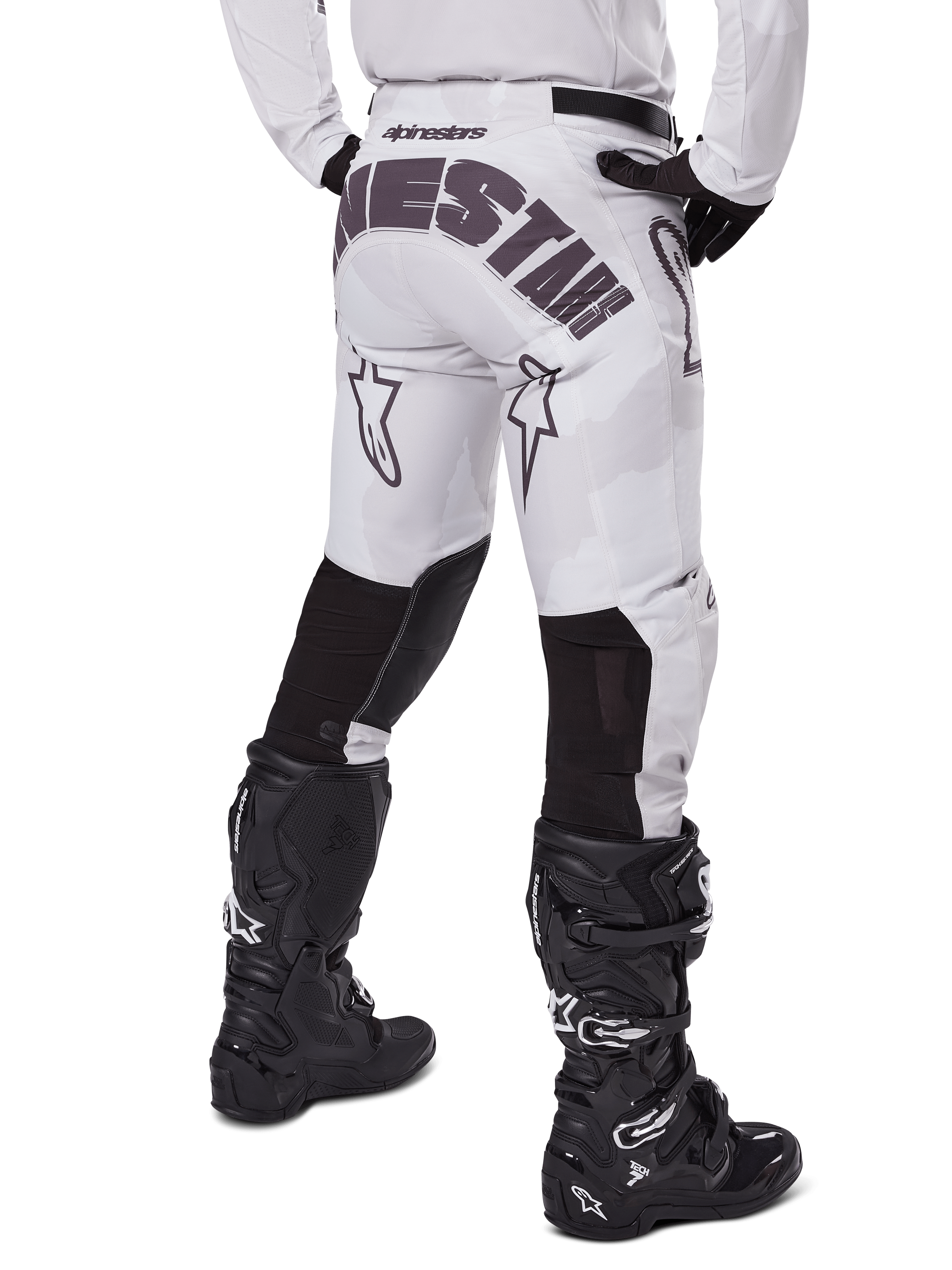 Alpinestars 2025 Racer Hollow Hose, Motocross-Hose, Light Camo Brown, Rückansicht des Fahrers mit großem Branding am Gesäß und schwarzen Stretch-Einsätzen an den Unterschenkeln, kombiniert mit schwarzen Tech 7 Stiefeln