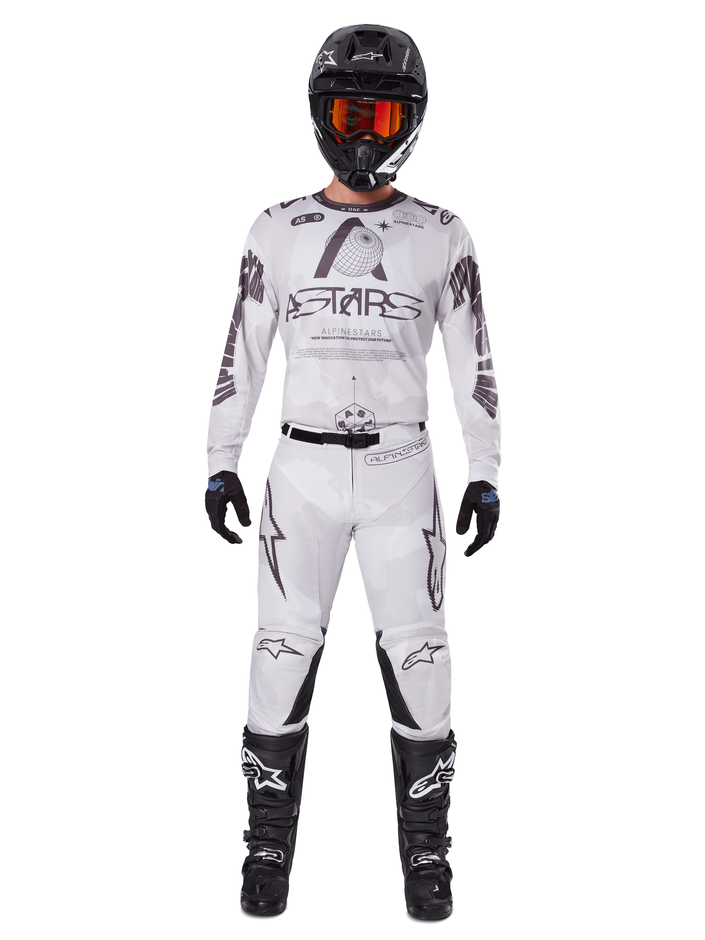 Motocross-Fahrer in der Alpinestars 2025 Racer Hollow Hose in Light Camo Brown, kombiniert mit einem passenden weiß-grauen Langarm-Trikot, schwarzem Helm mit orange-roter Brille, schwarzen Handschuhen und schwarzen Stiefeln, abgestimmtes Rennbekleidungs-Set für Offroad-Performance.