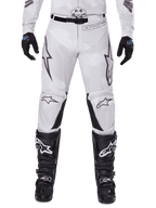Alpinestars 2025 Racer Hollow Hose, Motocross-Hose, Light Camo Brown, getragen mit schwarzen Handschuhen und Motocross-Stiefeln, mit dezentem Camouflage-Muster, schwarzen Grafikdrucken und Astars-Logos, ergonomisches Design für Performance-Offroad-Fahrten