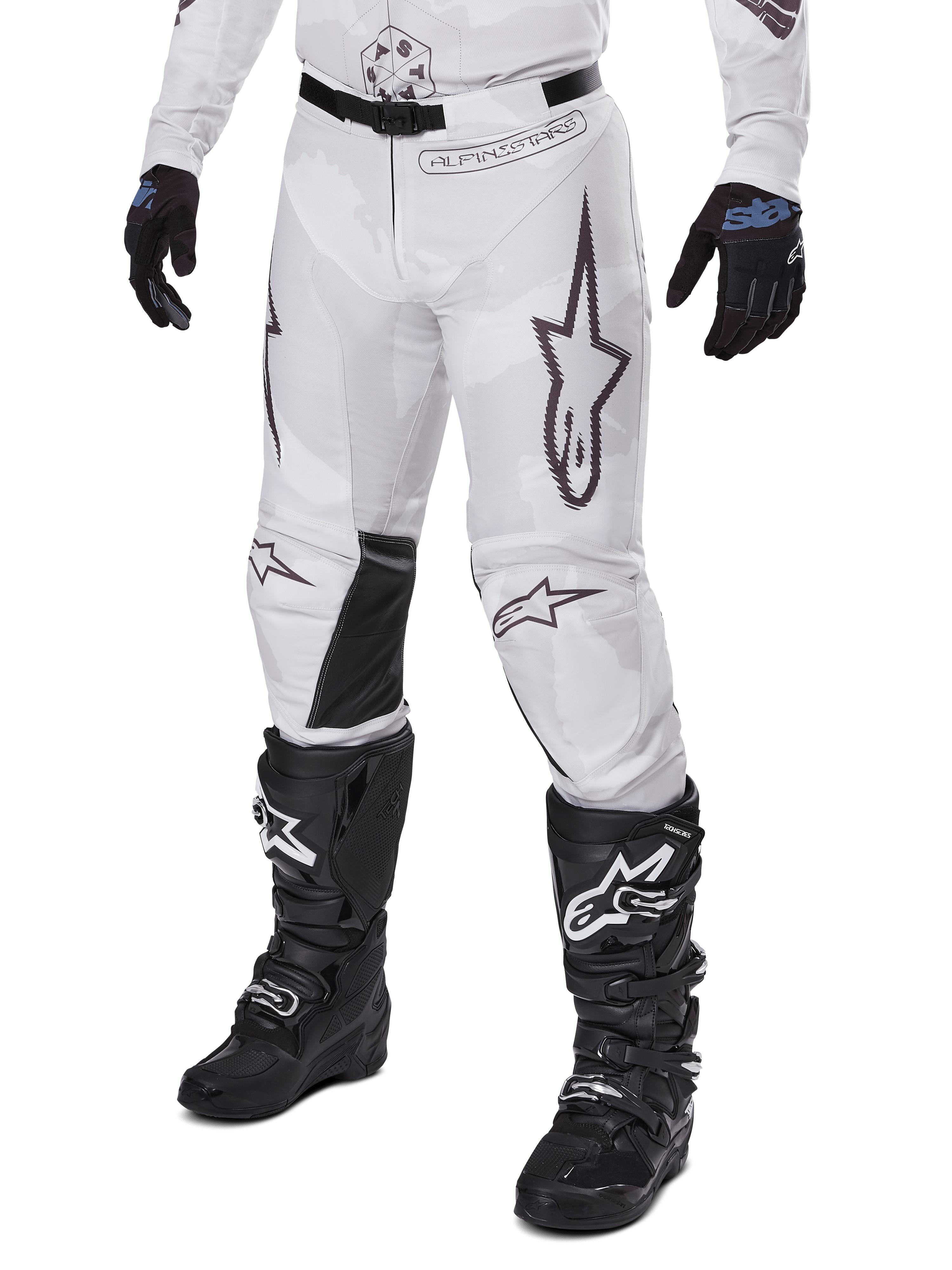 Alpinestars 2025 Racer Hollow Hose, Motocross-Hose, Weiß und Grau Camouflage, mit großen schwarz umrandeten Stern-Logos und schwarzen Leder-Innenknie-Einsätzen, kombiniert mit schwarzen Motocross-Stiefeln und Handschuhen, strapazierfähiges Design für Offroad-Rennsport
