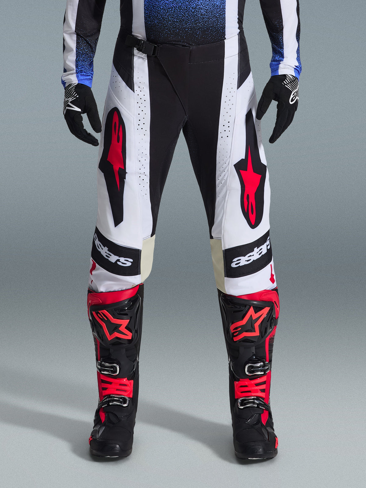 Alpinestars 2026 Techstar Knif Hose, Motocross-Hose, Schwarz, Weiß und Rot, getragen mit passenden rot-schwarzen Stiefeln und schwarzen Handschuhen, mit markanten roten Stern-Logos auf weißen Einsätzen und technischen perforierten Details für den Offroad-Rennsport.