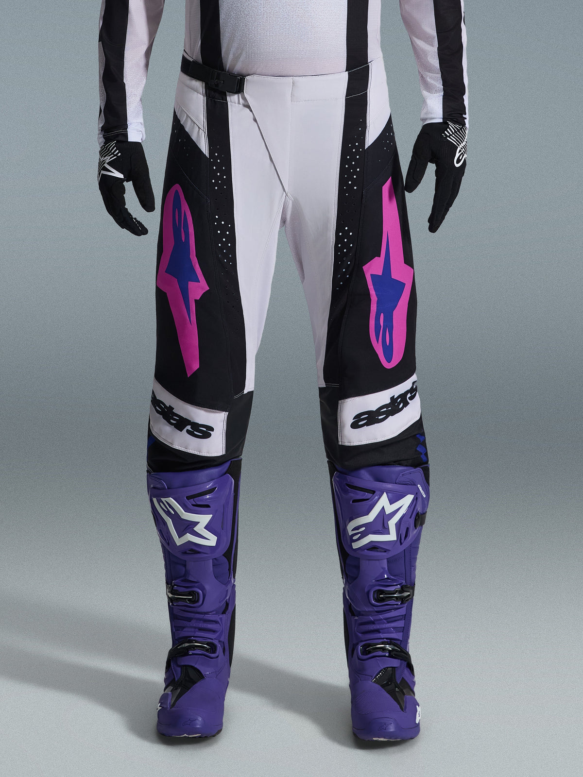 Alpinestars 2026 Techstar Knif Pants, Motocross Racing Pants, Black, White, and Purple with Pink and Blue accents, worn with purple racing boots and black gloves, featuring ergonomic racing cut and bold logo graphics for off-road performance