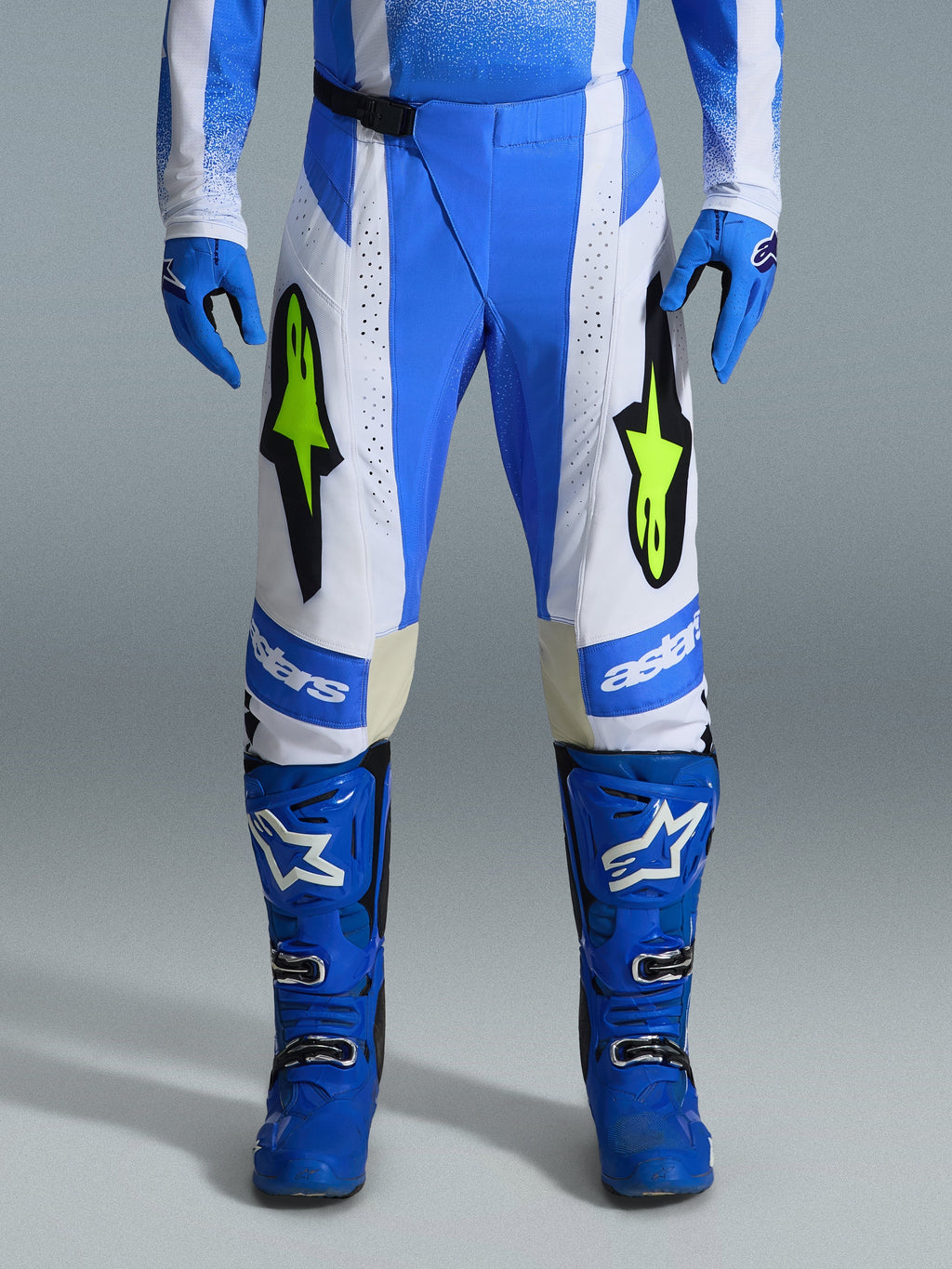 Alpinestars 2026 Techstar Knif Hose, Motocross-Hose, UCLA Blau, Schwarz und Fluo-Gelb, kombiniert mit passenden blauen Handschuhen und Stiefeln, mit weißen Einsätzen und leuchtenden gelben Fluo-Logos, ergonomische Racing-Passform für Offroad-Performance