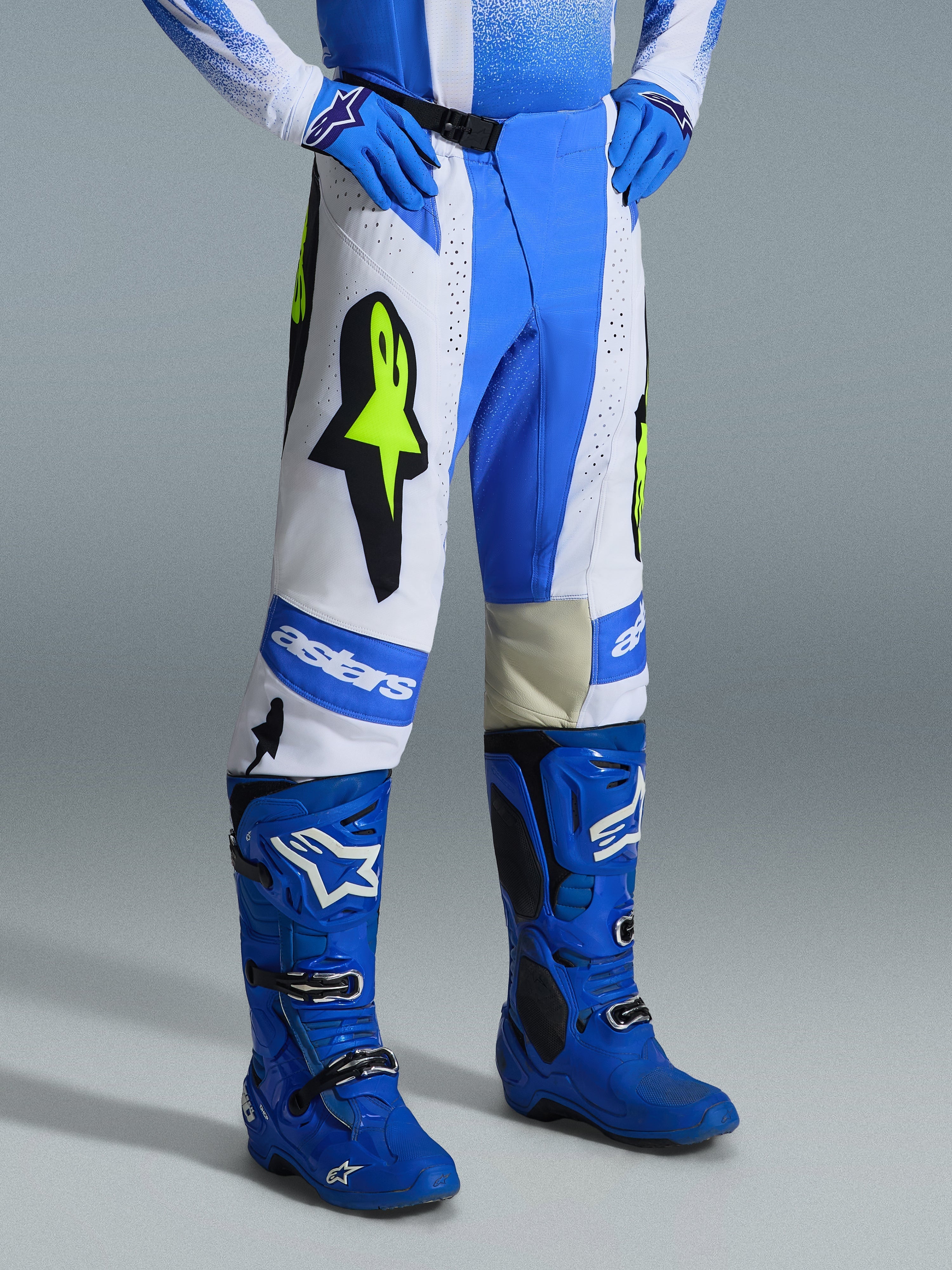 Alpinestars 2026 Techstar Knif Hose, Motocross-Hose, UCLA Blau, Schwarz und Gelb Fluo, getragen mit passenden blauen Motocross-Stiefeln und Handschuhen, mit weißen Einsätzen, großen gelben Fluo-Sternlogos und sportlichem Offroad-Design