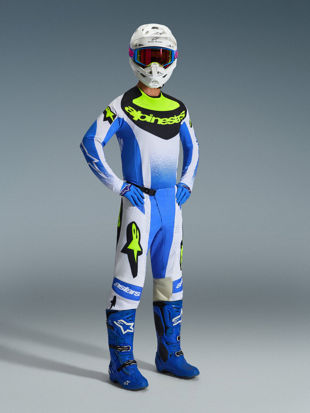 Motocross-Fahrer in Alpinestars 2026 Techstar Knif Hose in Ucla Blue, Schwarz und Gelb Fluo, komplettes Gear Set mit passendem Jersey und auffälligem Alpinestars-Branding, blauen Stiefeln, weißem Helm mit Goggles und blauen Handschuhen, athletische Pose für Offroad-Performance
