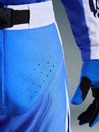 Alpinestars 2026 Techstar Knif Hose, Ucla Blau und Weiß, Nahaufnahme des Hüftbereichs mit lasergeschnittenen Perforationen zur Belüftung, SX2-Magnetverschluss am Bund und passenden Motocross-Handschuhen
