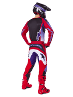 Motocross-Fahrer von hinten in Alpinestars 2025 Fluid Wurx Hose, Purple Bright Red mit weißen und schwarzen Akzenten, passendes Trikot, schwarzer Helm und rote Stiefel, abgestimmtes Outfit für den Offroad-Rennsport