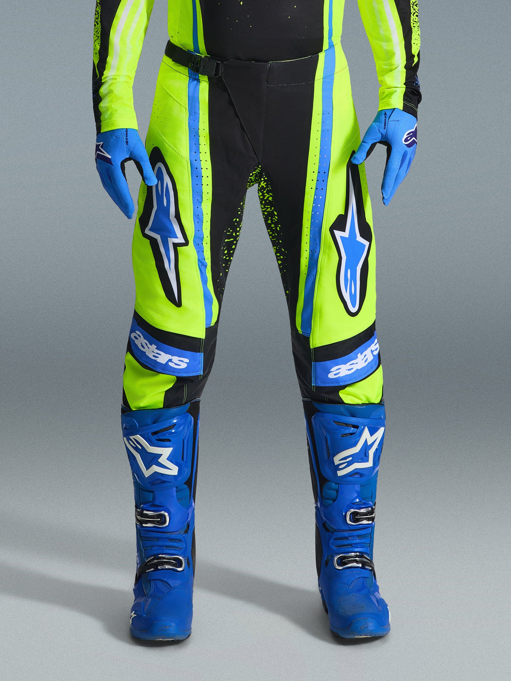 Alpinestars 2026 Techstar Nomur Hose, Motocross-Hose, Gelb Fluo und Dunkelblau mit blauen Akzenten, getragen mit passenden blauen Handschuhen und Stiefeln, mit markanten Astars-Logos an den Oberschenkeln und einem leistungsoptimierten Design für den Offroad-Rennsport.