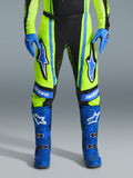 Alpinestars 2026 Techstar Nomur Hose, Motocross-Hose, Gelb Fluo und Dunkelblau mit blauen Akzenten, getragen mit passenden blauen Handschuhen und Stiefeln, mit markanten Astars-Logos an den Oberschenkeln und einem leistungsoptimierten Design für den Offroad-Rennsport.