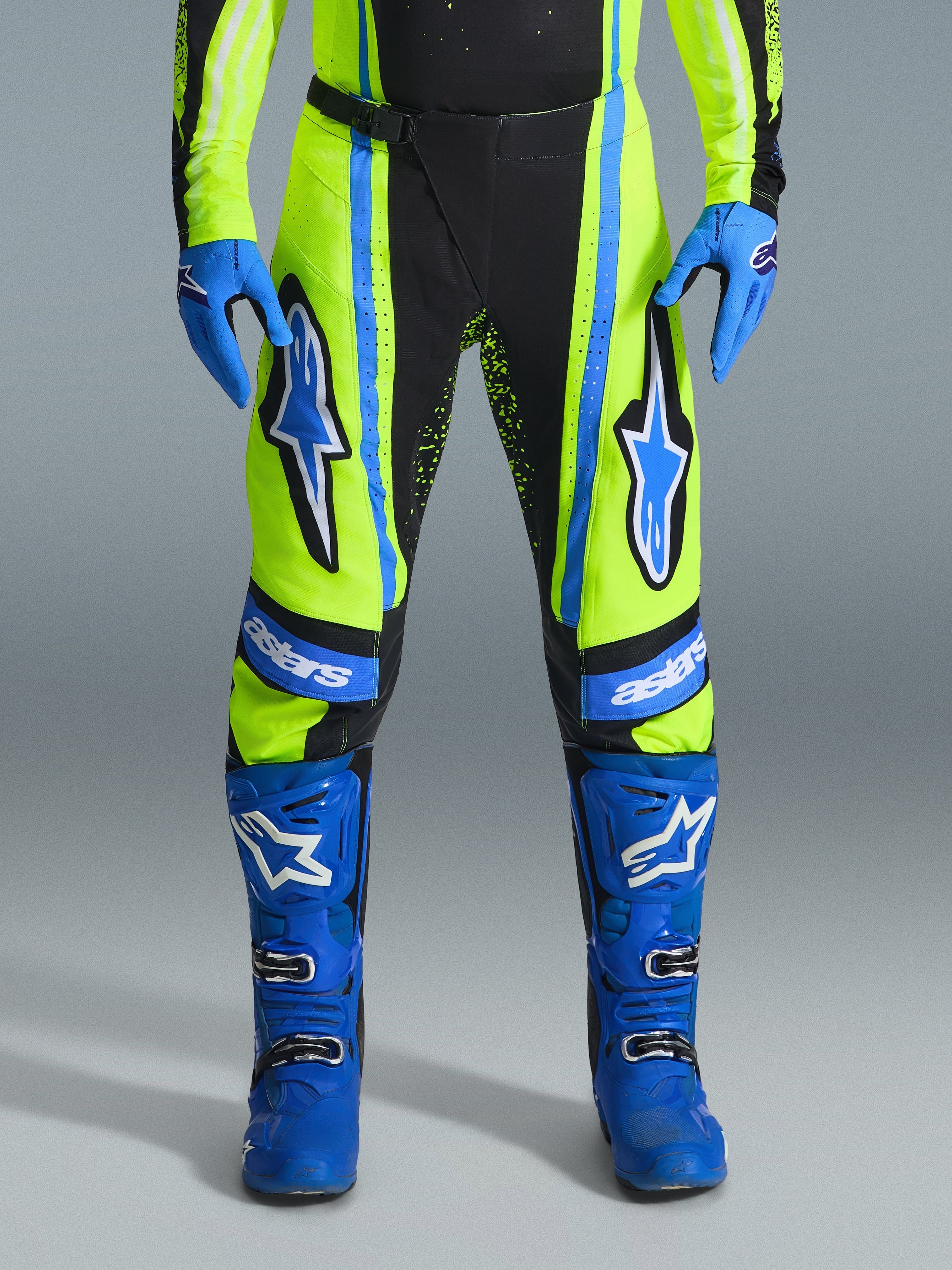 Alpinestars 2026 Techstar Nomur Hose, Motocross-Hose, Gelb Fluo und Dunkelblau mit blauen Akzenten, getragen mit passenden blauen Handschuhen und Stiefeln, mit markanten Astars-Logos an den Oberschenkeln und einem leistungsoptimierten Design für den Offroad-Rennsport.