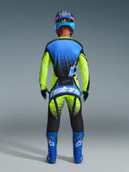Motocross-Fahrer in der Rückansicht, Alpinestars 2026 Techstar Nomur Hose in Gelb Fluo und UCLA Blue mit dunkelblauen Akzenten, passendes Trikot und blaue Stiefel, markantes Astars-Branding am Gesäß, gesprenkeltes Grafikdesign.